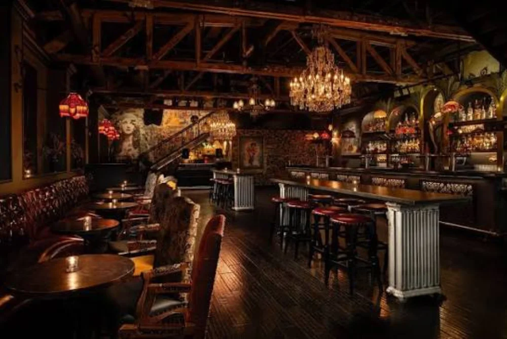 A dimly lit bar and dining room with chandeliers